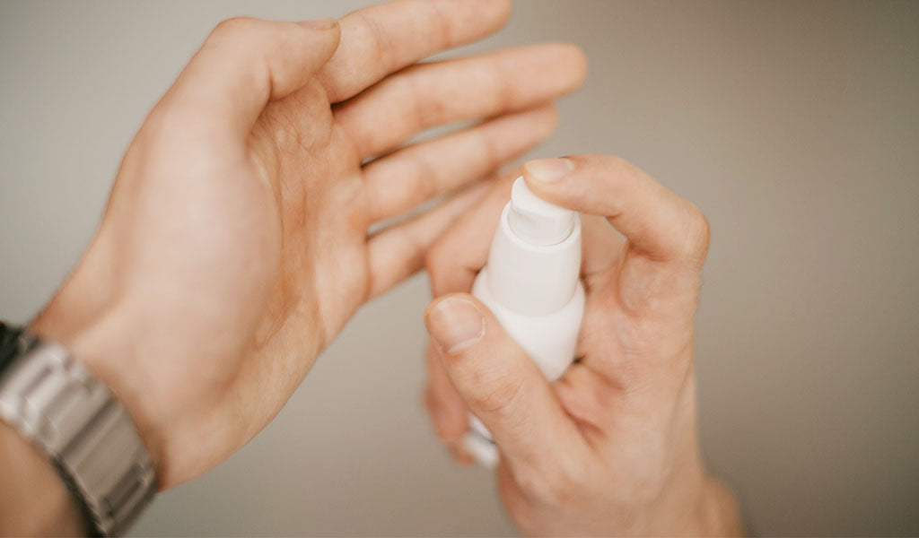 Hands dispensing skincare serum from a white pump bottle