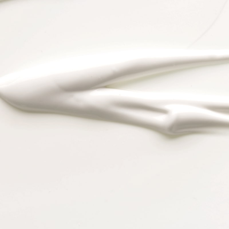 Smear of white moisturizing cream spread on a smooth pale surface