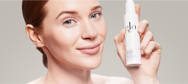Smiling woman holding a white bottle labeled glo next to her face