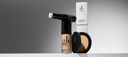 Front view of Glo Skin Beauty makeup collection showcasing assorted containers and a compact with a gray background
