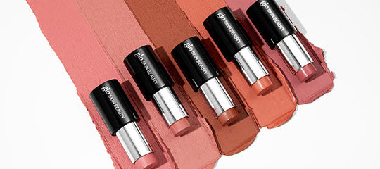 Five Glo Skin Beauty cream blush sticks arranged on matching blush swatches, shades from mauve to terracotta.