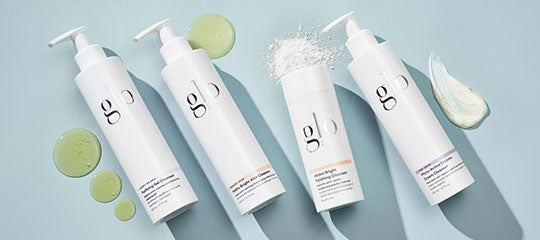 Four white bottles of Glo skincare products with different textures on a light blue background