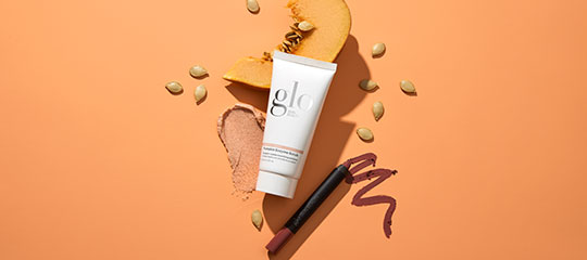 glo skincare tube with pumpkin powder and seeds, plus two mauve lip crayons and swatches on an orange background