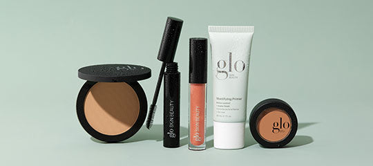 Assorted glo cosmetic products including powder compact, mascara, lip gloss and tube labeled 'Mattifying Primer'