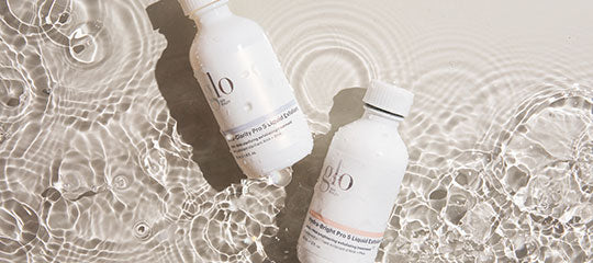 Two white glo skincare bottles floating in rippling water, top-down view.