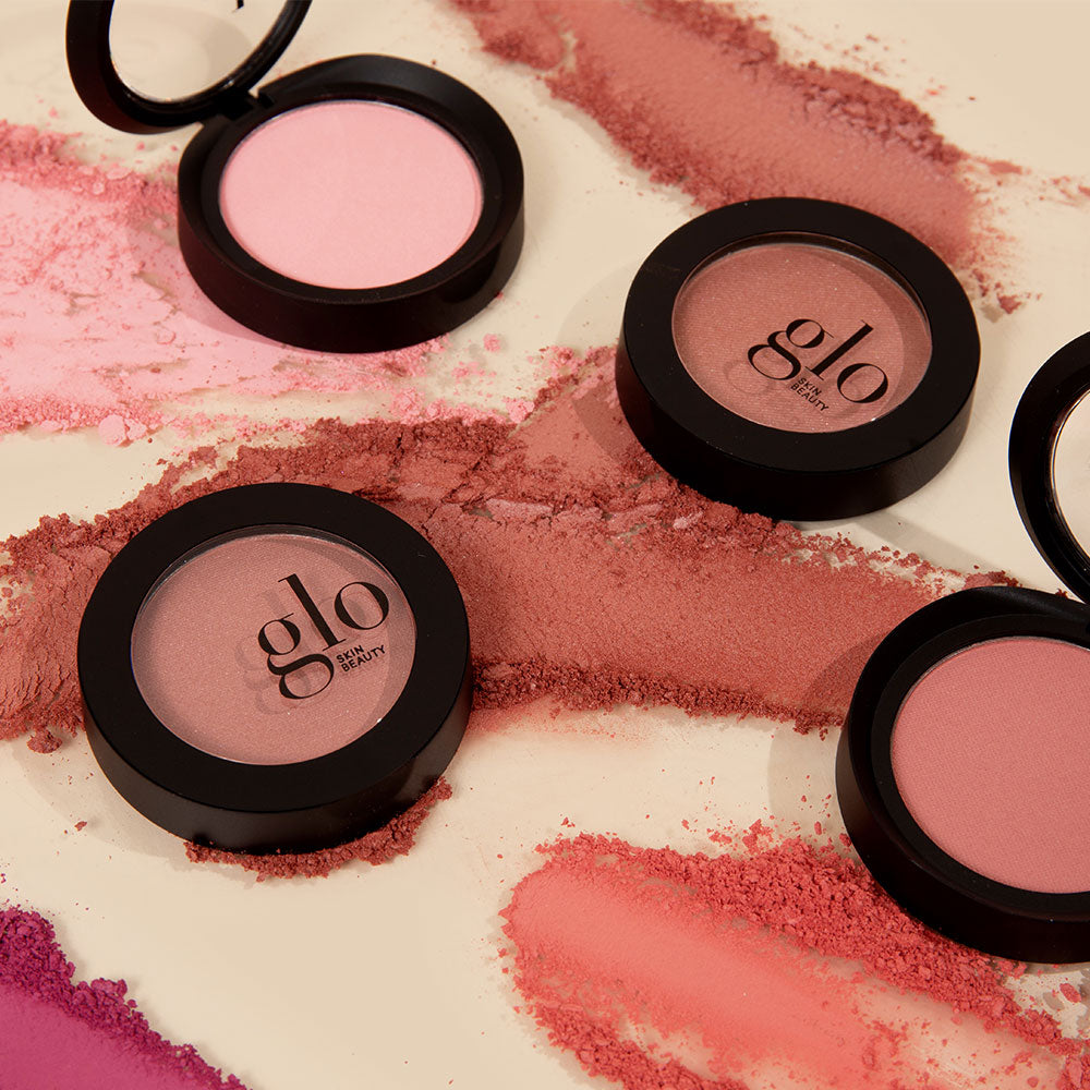 Multiple shades of blush powder compacts with 'glo skin beauty' branding on a beige surface