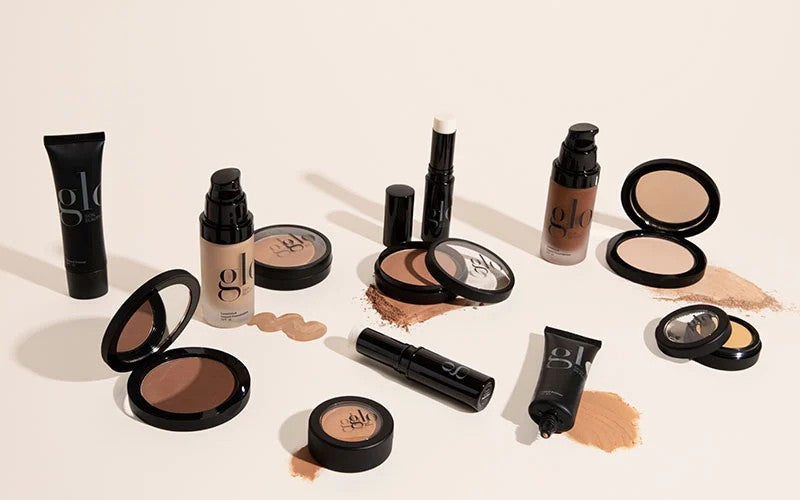 Assorted glo brand foundations, compacts, and sticks with swatches on a light background.