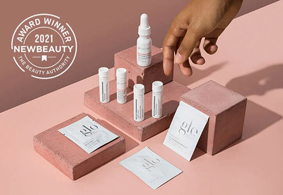 glo sachets, vials, dropper on pink blocks with hand; badge: AWARD WINNER 2021 NEWBEAUTY THE BEAUTY AUTHORITY