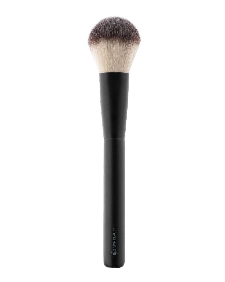 Round-topped black powder brush with light-to-dark synthetic bristles; handle stamped glo SKIN BEAUTY.