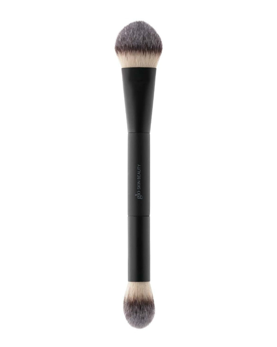 Double-ended black makeup brush with rounded bristles and 'glo SKIN BEAUTY' logo on the handle.