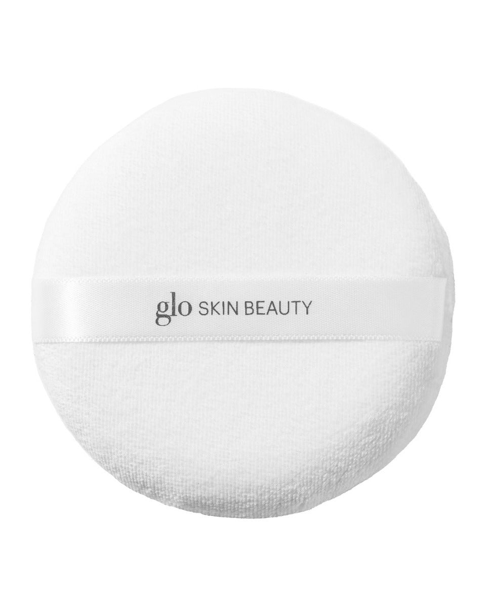 White round powder puff with 'glo SKIN BEAUTY' printed on the ribbon