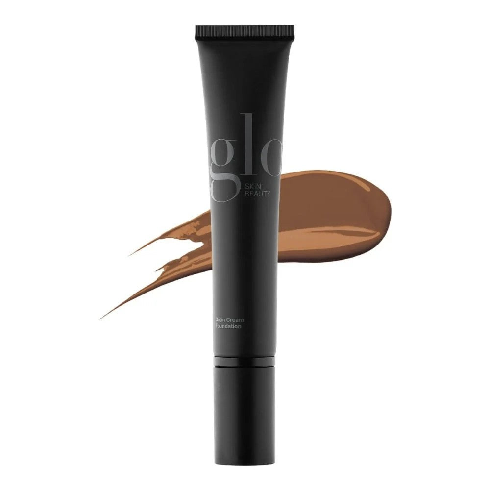 Black tube of glo SKIN BEAUTY Satin Cream Foundation with brown foundation smear behind