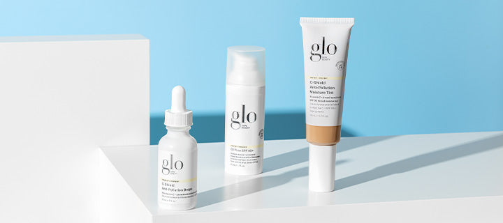 Three glo skincare products on a white platform against a blue background: dropper bottle, pump bottle, and tinted tube.