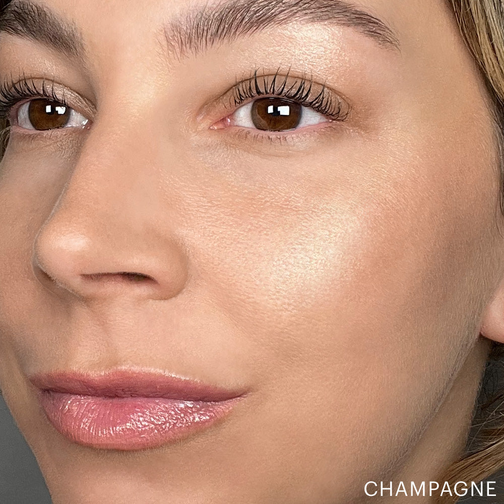 Close-up of a woman's face showing Skin Glow Stick Highlighter effect in shade Champagne on cheekbone
