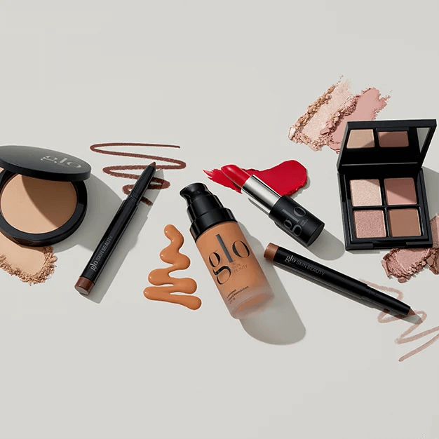 'glo' makeup items and swatches: foundation bottle, lipstick, eyeshadow quad, compact, pencil labeled 'glo skin beauty'