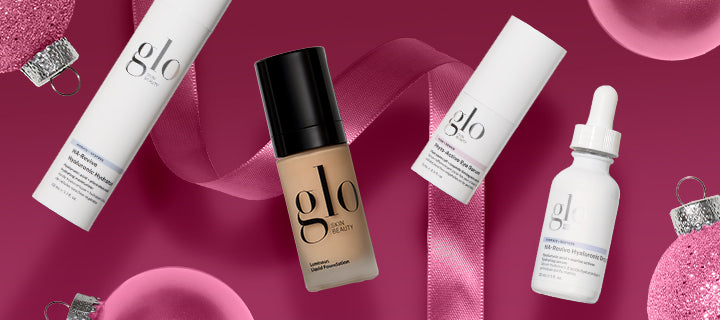 glo Skin Beauty foundation and skincare bottles arranged on pink background with ribbon and holiday ornaments