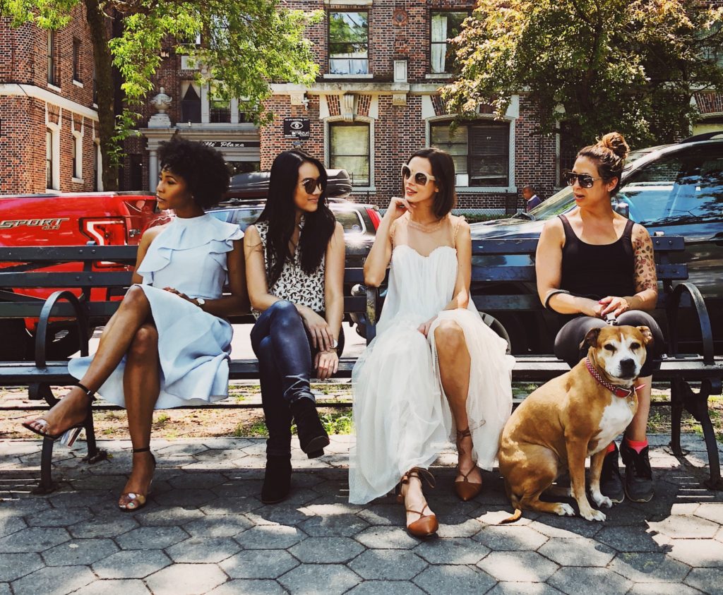 Group of women sitting on park bench with dog