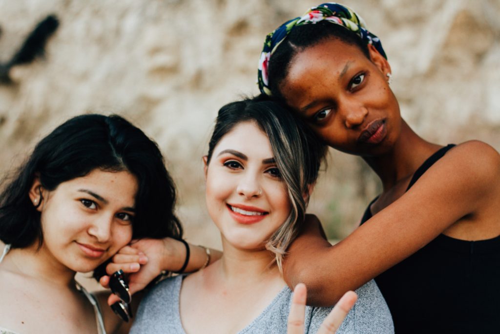 three women smiling with arms around