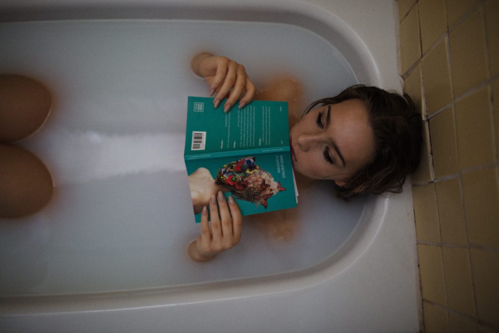 Woman reading book in bathtub