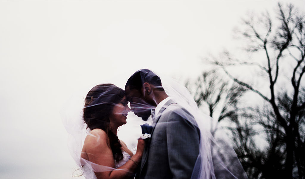 Bride and groom under veil outdoors