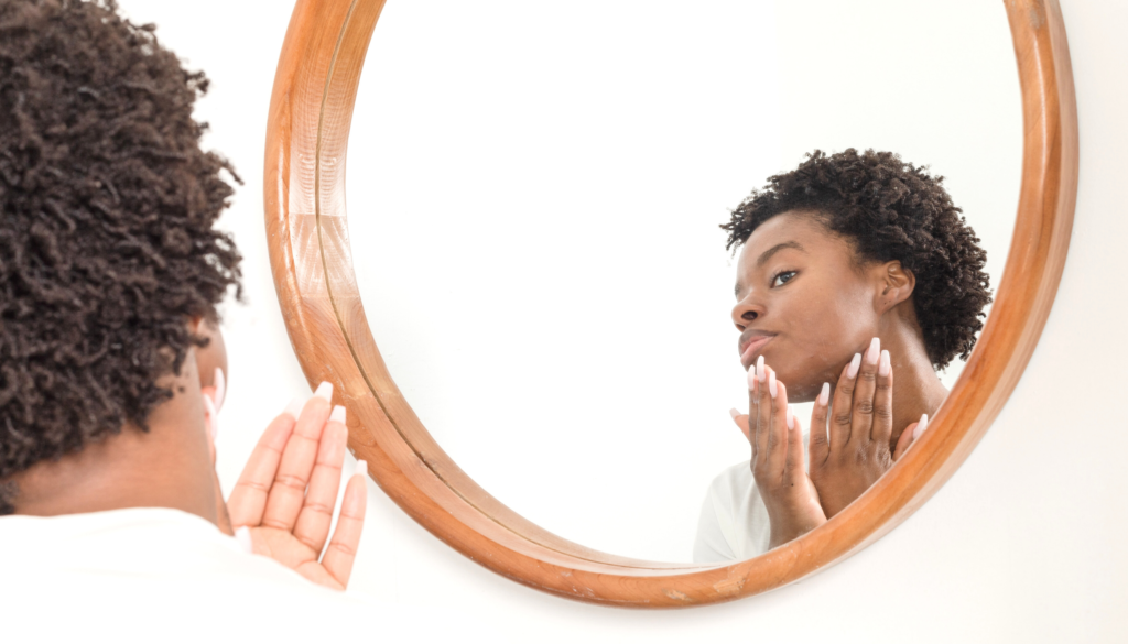 woman looking in mirror touching face