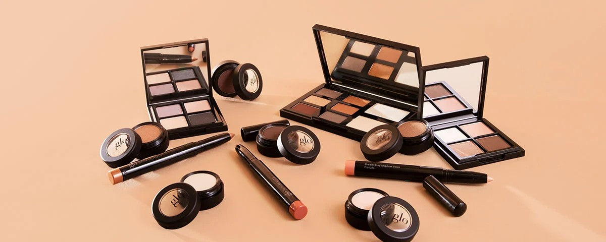 glo eyeshadow palettes, cream pots, and shadow sticks arranged on a beige background
