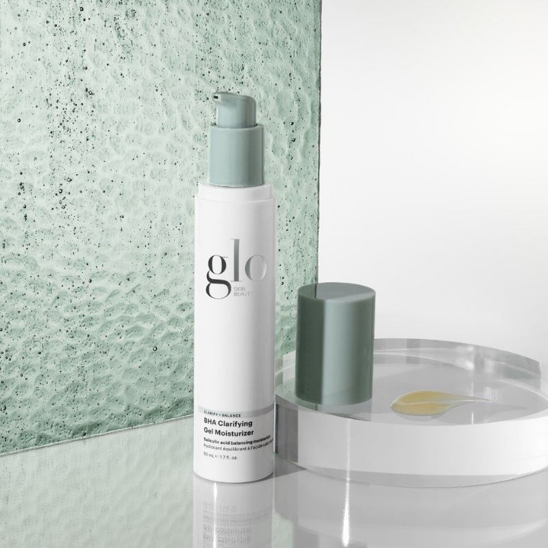 White pump bottle labeled glo SKIN BEAUTY; CLARITY + BALANCE; BHA Clarifying Gel Moisturizer on green textured background