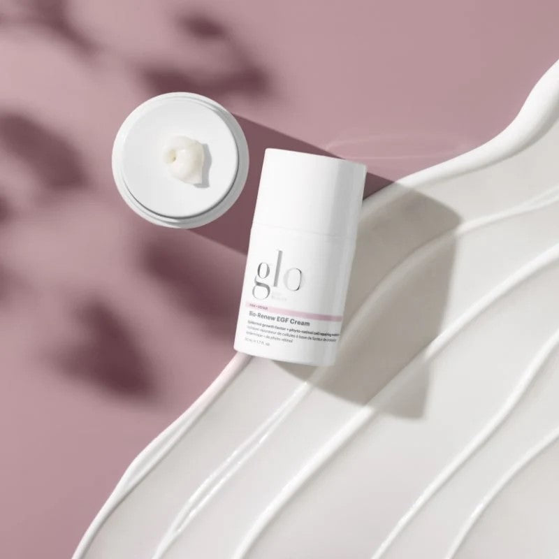 glo Bio-Renew EGF Cream bottle with open jar and cream dollop on pink background over white cream smear