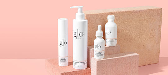 glo branded skincare bottles and pump arranged on pink brick platforms