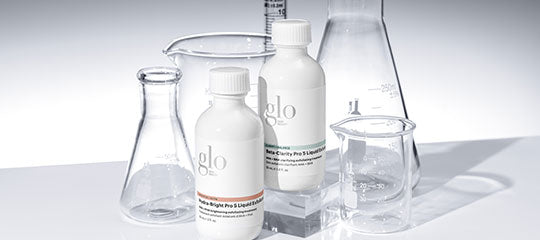 Two white bottles labeled 'glo' with laboratory glassware including beakers and flasks on a white surface