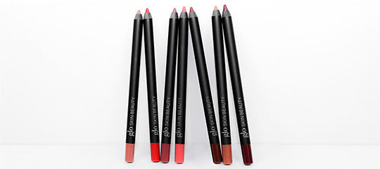 GLO SKIN BEAUTY black lip-liner pencils in pink, red and brown shades arranged upright and leaning.