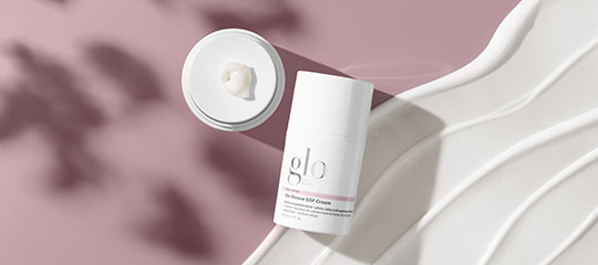 glo Bio-Renew EGF Cream bottle with a cream dollop on pink background with sculpted white waves