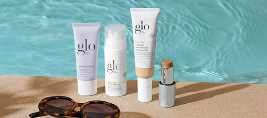 Glo Skin Beauty travel skincare products arranged on a poolside ledge with sunglasses and turquoise water