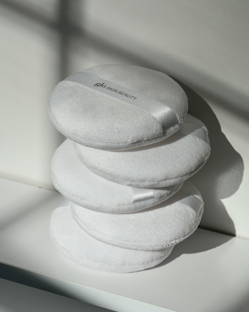 Stack of four white powder puffs with 