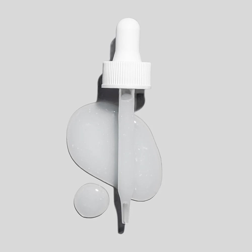 White dropper pipette on light-gray background with glossy serum drop, smaller droplet, and elongated spill