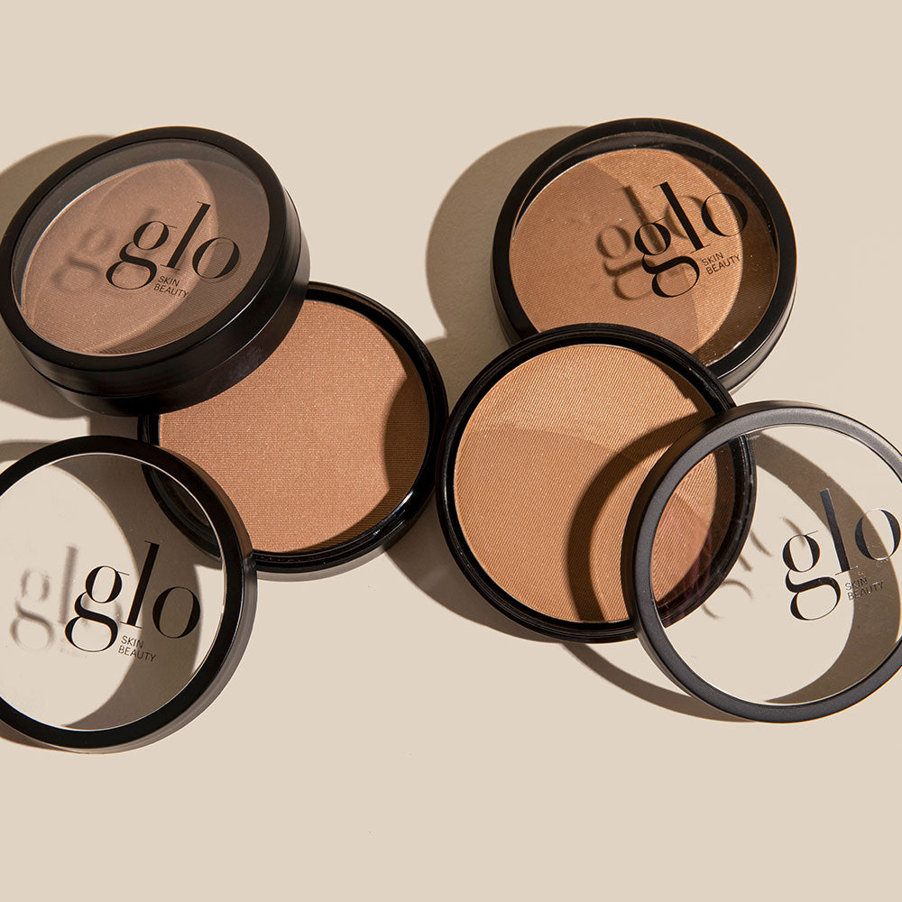 Four open bronzer compacts with 'glo SKIN BEAUTY' on lids in varying bronze shades