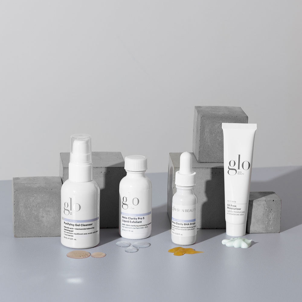 Four white glo skincare bottles and tubes on gray concrete blocks with small product swatches.
