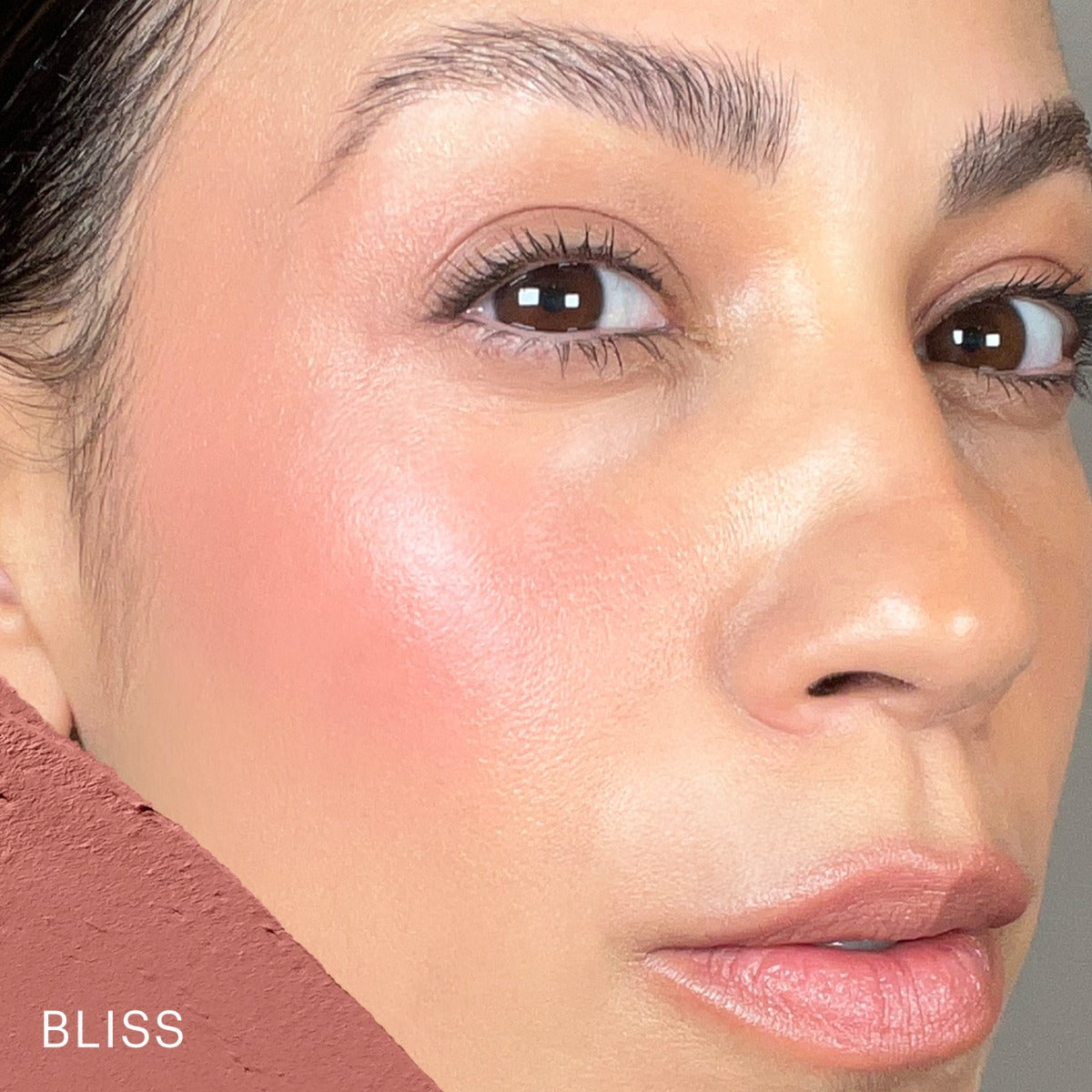 Close-up portrait showing warm pink cream blush on cheekbone and swatch labeled BLISS.