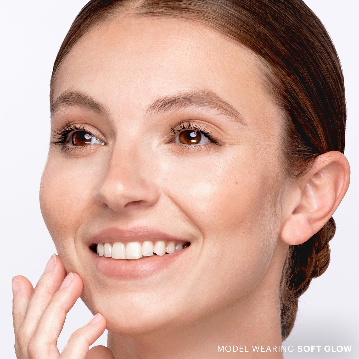 Close-up smiling woman with clear skin; bottom-right text reads 'MODEL WEARING SOFT GLOW'.