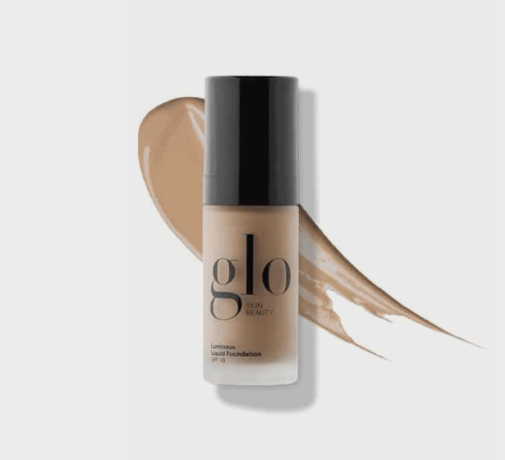 Glo Skin Beauty Luminous Liquid Foundation bottle with beige foundation swatch behind