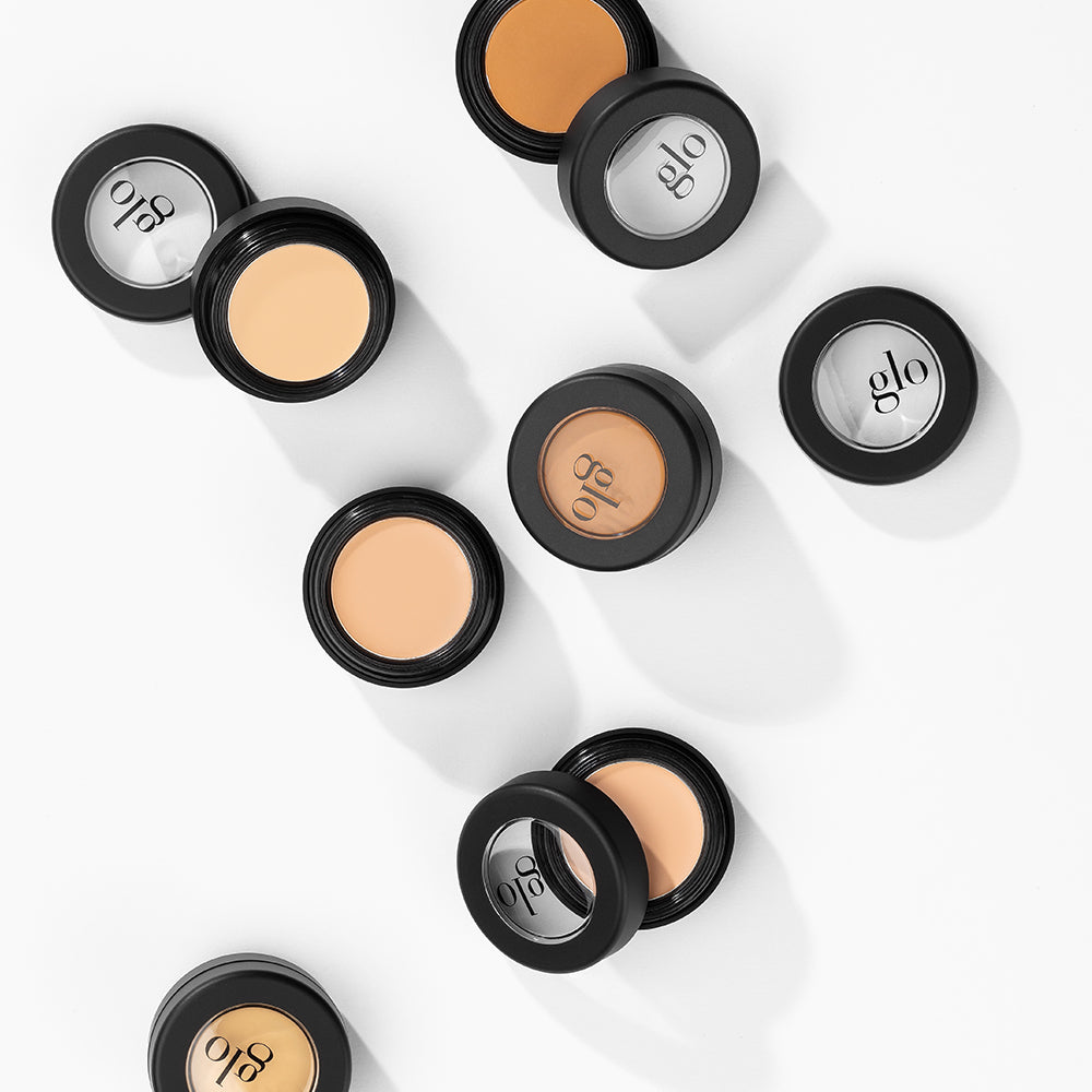 Makeup containers with shades of concealer and brand name glo on lids