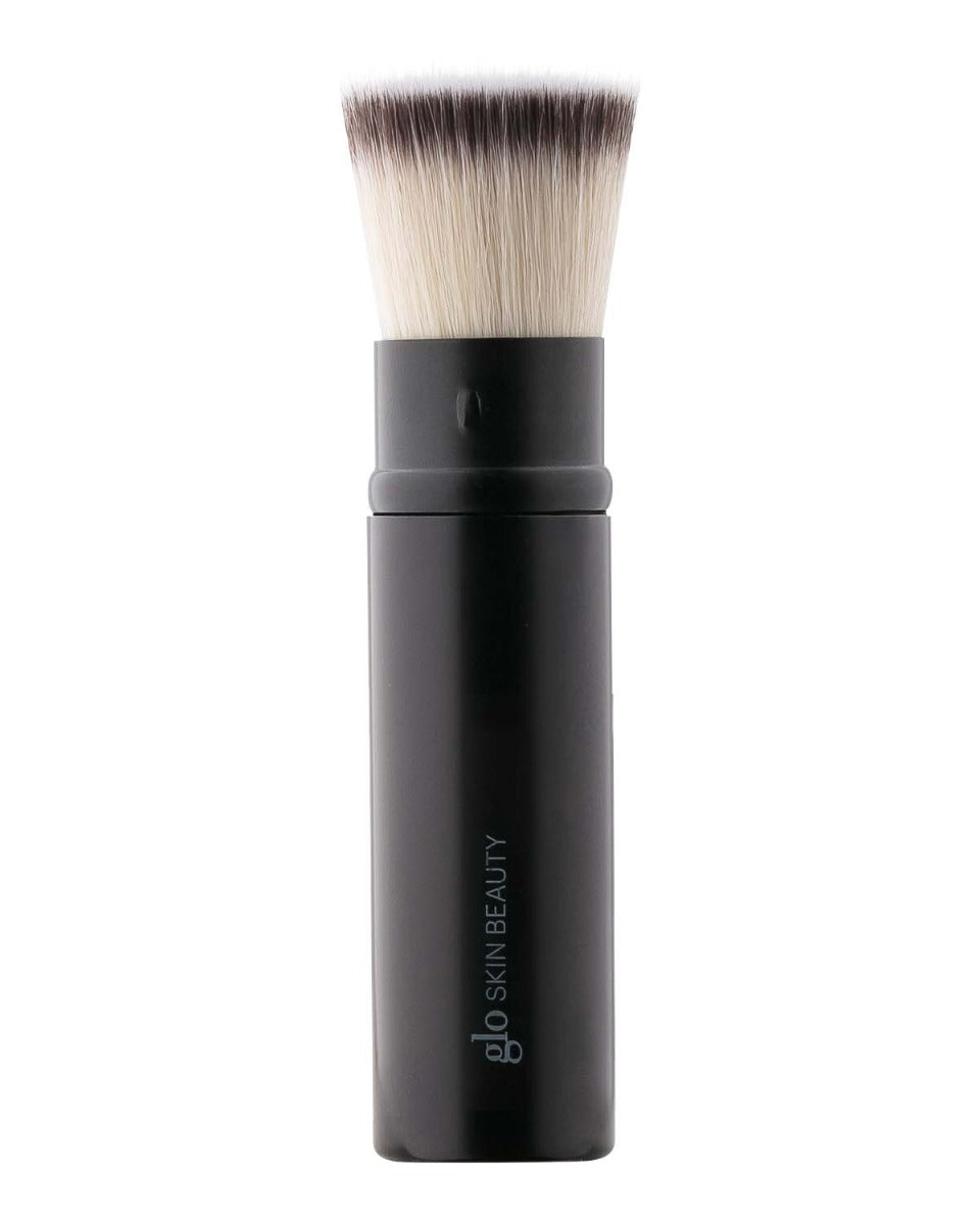 Retractable flat-top foundation brush with black handle labeled 'glo SKIN BEAUTY'.