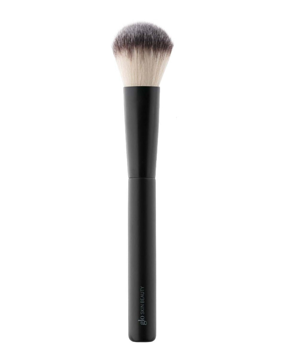 Large soft powder makeup brush with black handle and light-to-dark bristles labeled 'glo SKIN BEAUTY'.
