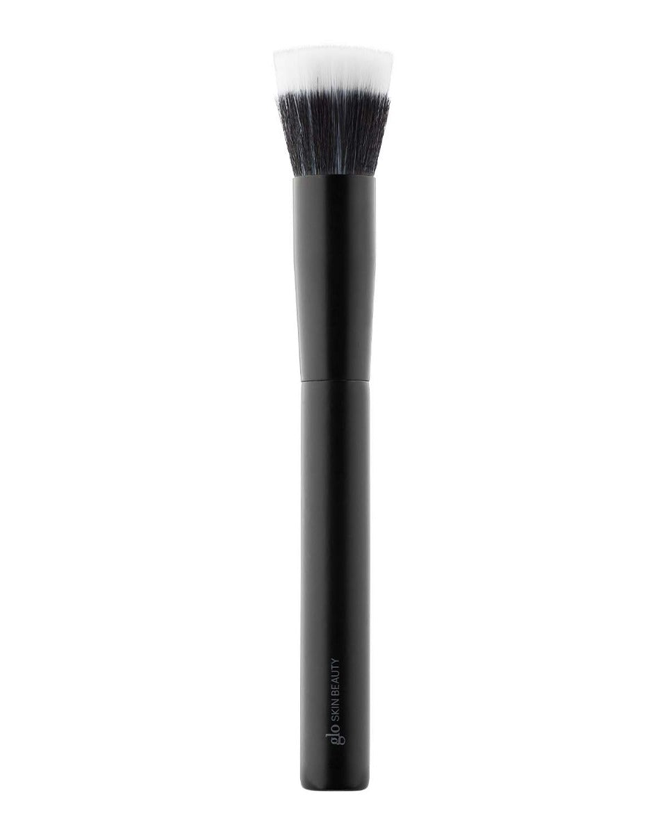 Makeup brush with black handle and white-tipped bristles, brand text 