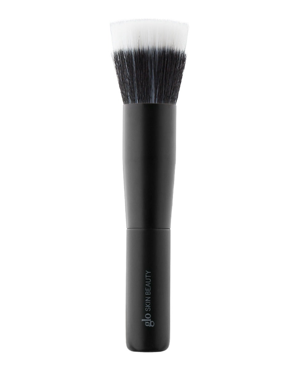 Compact dual-fiber cheek brush with black handle and white-tipped bristles; handle text: 