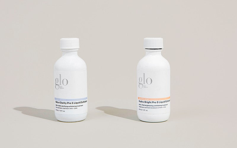 Two white glo bottles labeled 'Beta-Clarity Pro 5 Liquid Exfoliant' and 'Hydra-Bright Pro 5 Liquid Exfoliant'