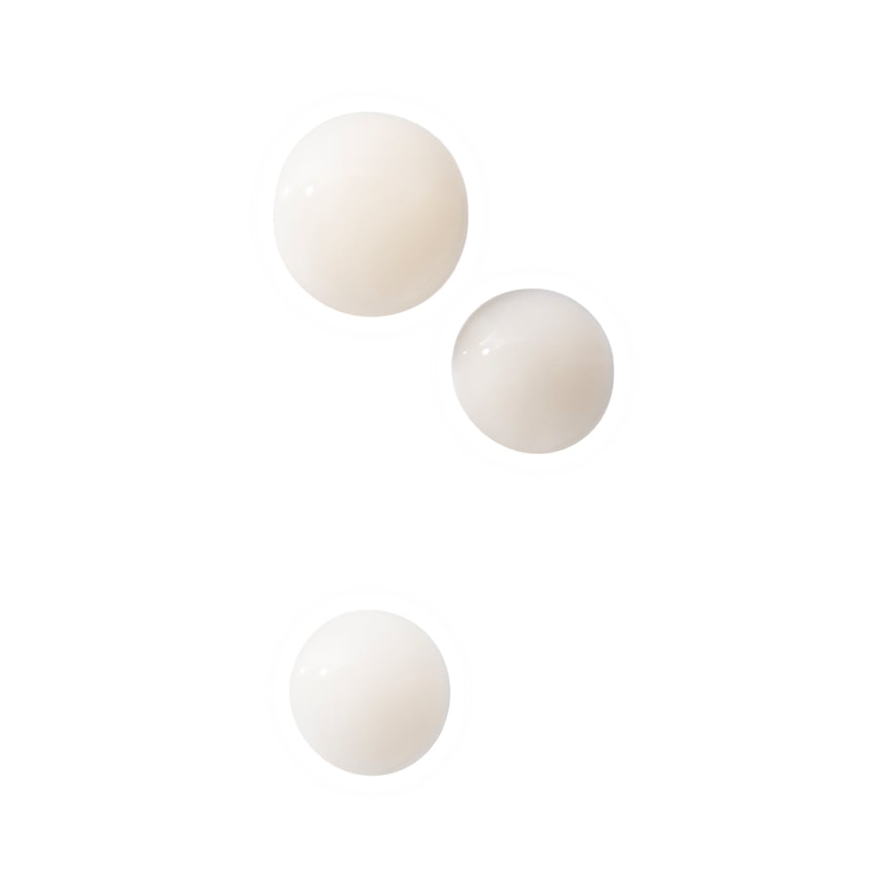 Three glossy pale beige cream droplets on a white background, two near the top and one lower.