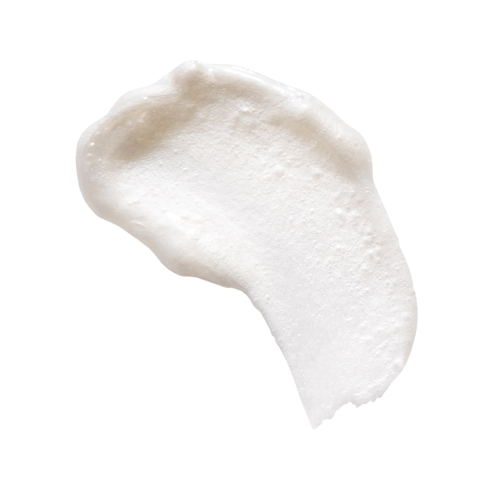 Creamy white cleanser swatch with textured, bubbly surface on a white background.