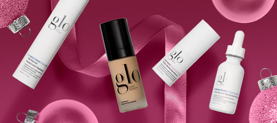 glo cosmetic products: foundation bottle, serum dropper, and skincare tubes arranged on a pink ribbon with ornaments