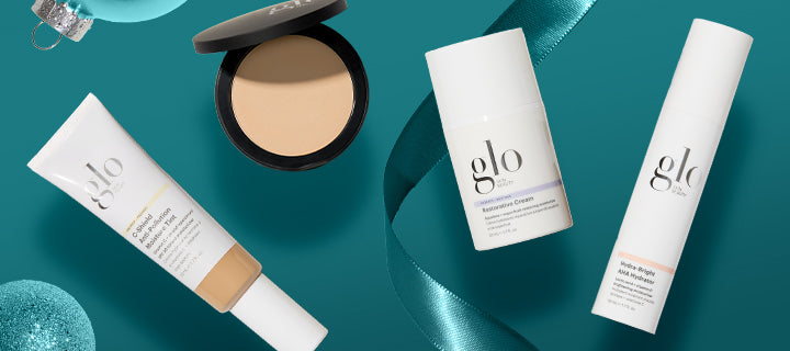 Flat lay of glo brand skincare and makeup products — tube, compact powder, and two pump bottles on teal background.